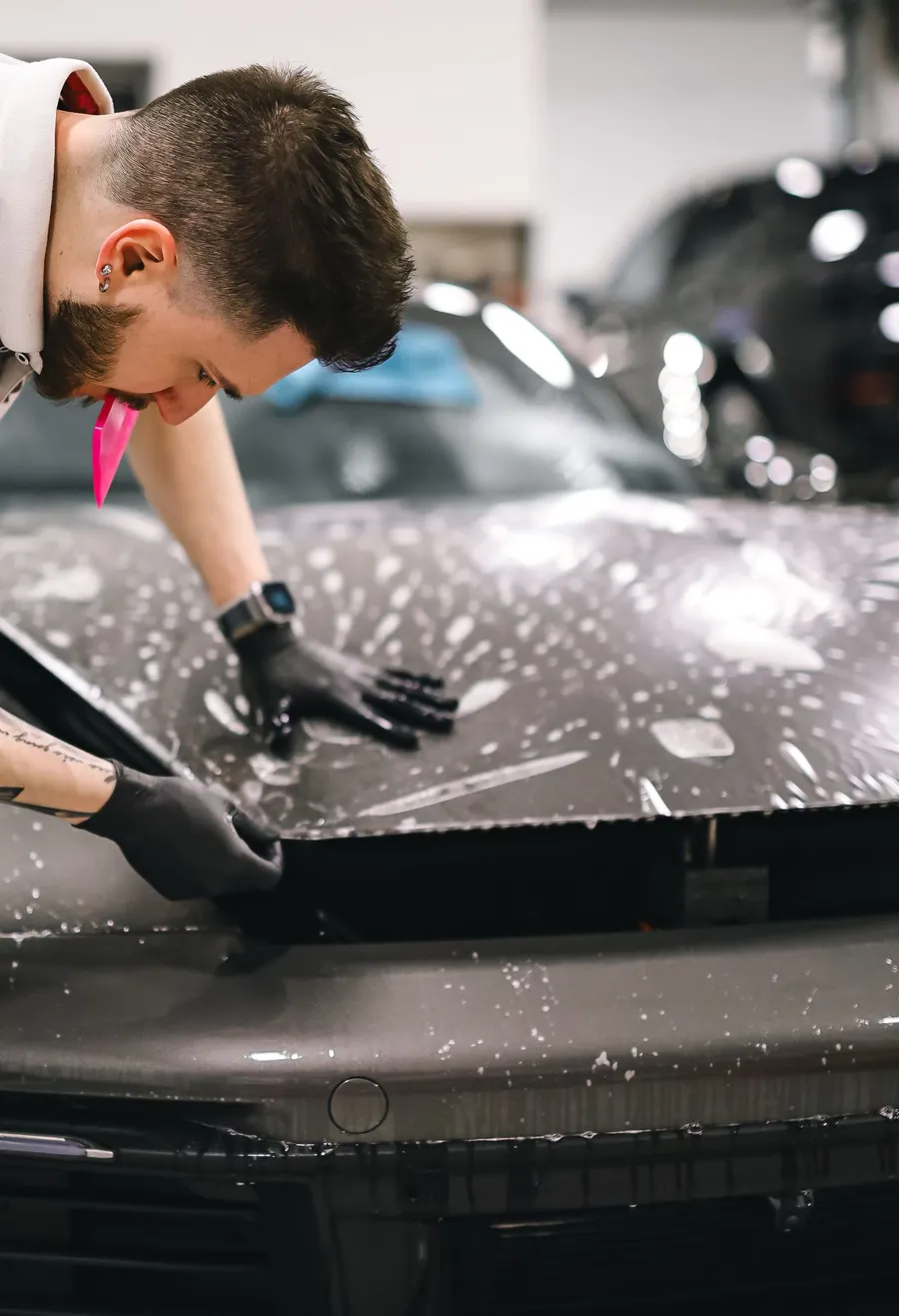 Installer applying paint protection film to a car hood